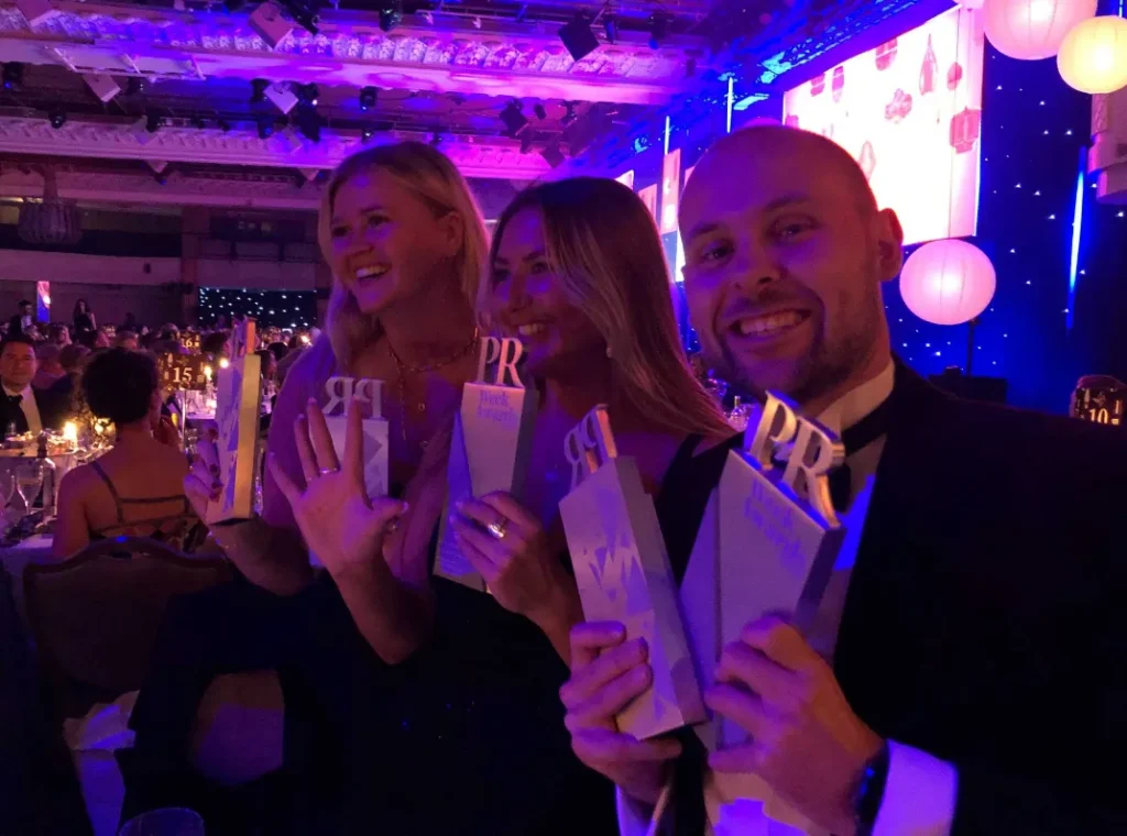 Three people at an awards ceremony holding awards