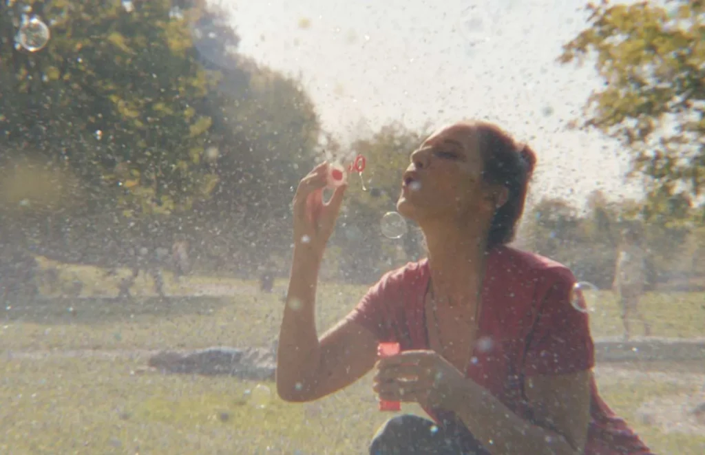 Woman blowing bubbled in a green park
