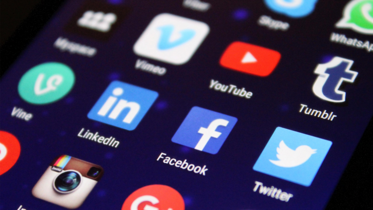 Close-up of a smartphone screen displaying various social media app icons, including Meta platforms, Vimeo, YouTube, Tumblr, Vine, LinkedIn, Facebook, Twitter, Instagram, and WhatsApp arranged in a grid.