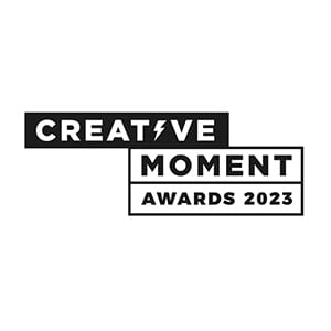 Black and white logo with the text CREATIVE MOMENT in bold, uppercase letters, and AWARDS 2023 in a box below. The V in CREATIVE is stylized as a lightning bolt.