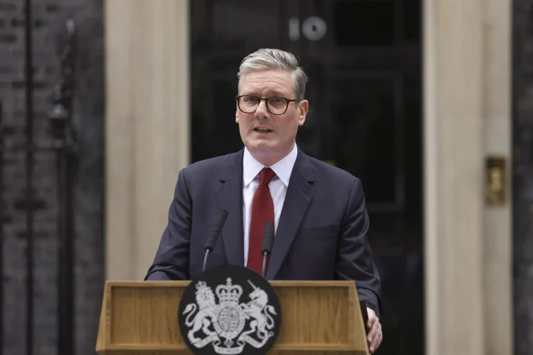 A man in a suit and red tie delivers a Rose Garden Speech at a podium with the UK government crest in front of 10 Downing Street, embodying the poise of a true Political Insider.